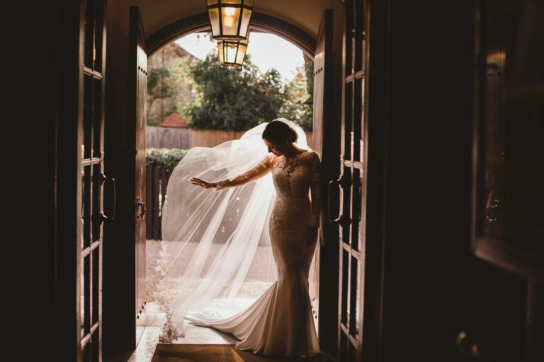 The bride backlit in the doorway, her veil trailing behind her, The Montagu Arms Hotel