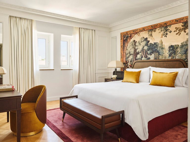 A bedroom with a tapestry panel above the bed and a bench at its foot, The Palace, a Luxury Collection Hotel, Madrid
