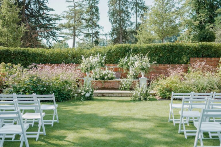 A garden ceremony laid out on the lawn below brick-walled flower terraces and a yew hedge, The Post Barn