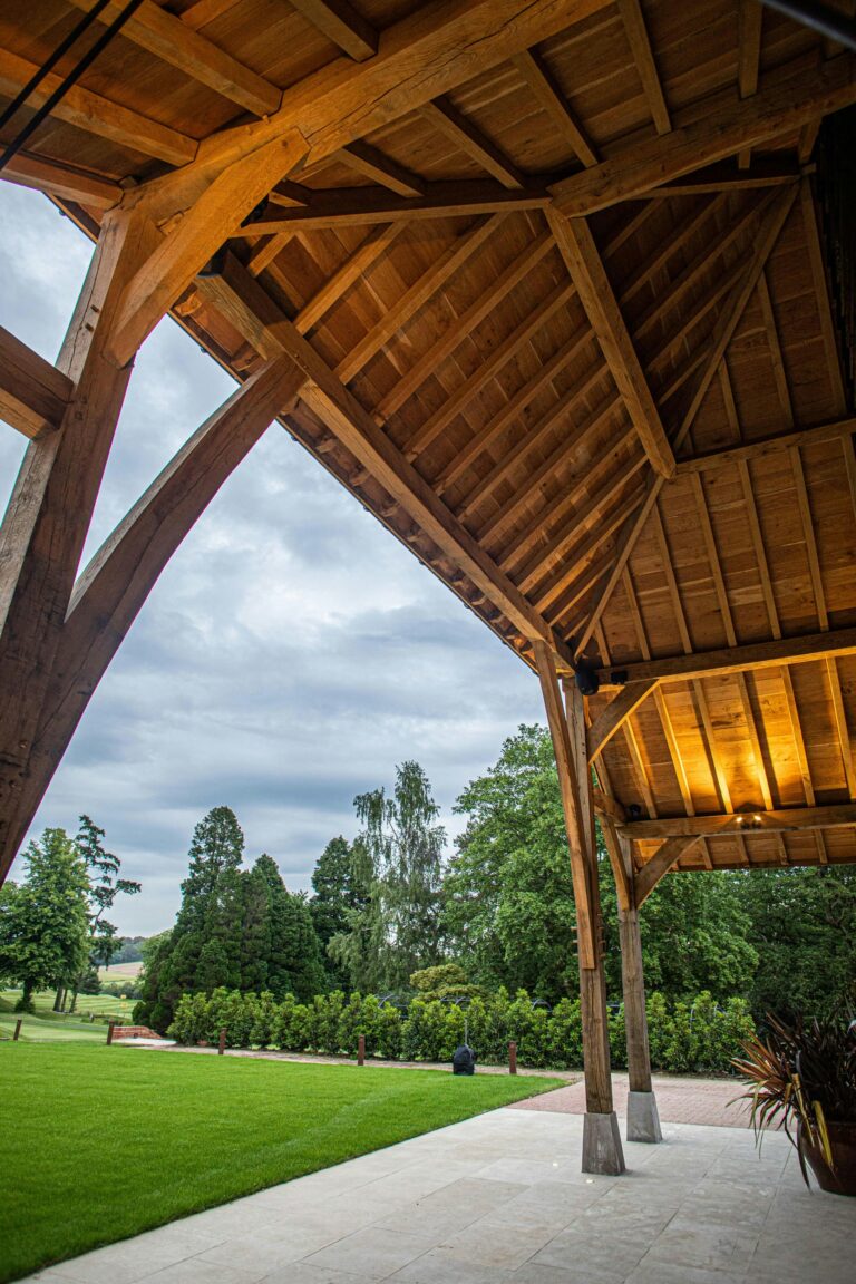 Oak posts and braces of the covered walkway framing the lawn, The Post Barn