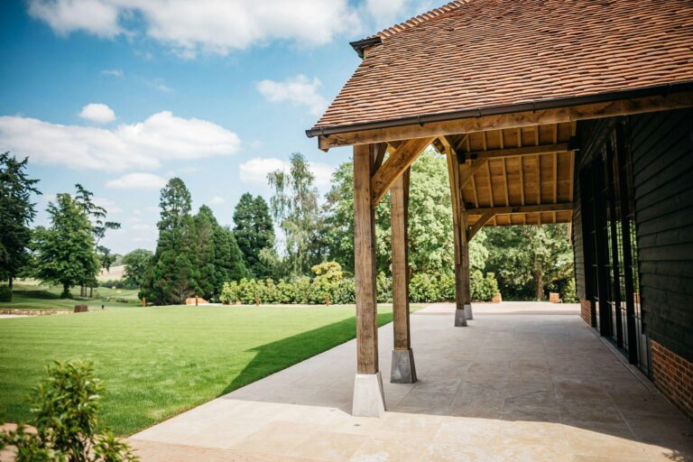 The covered oak walkway along the barn looking out over the lawn and parkland trees, The Post Barn