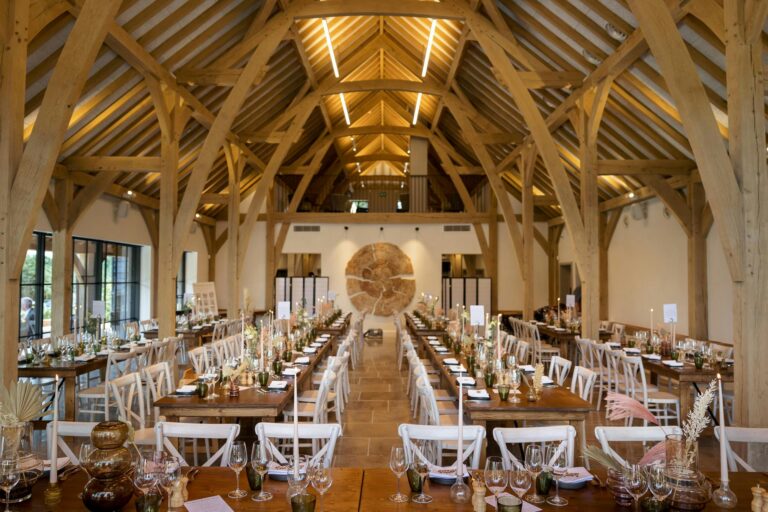 Long wooden tables laid for dinner down the length of the barn, with the mezzanine and timber roof above, The Post Barn