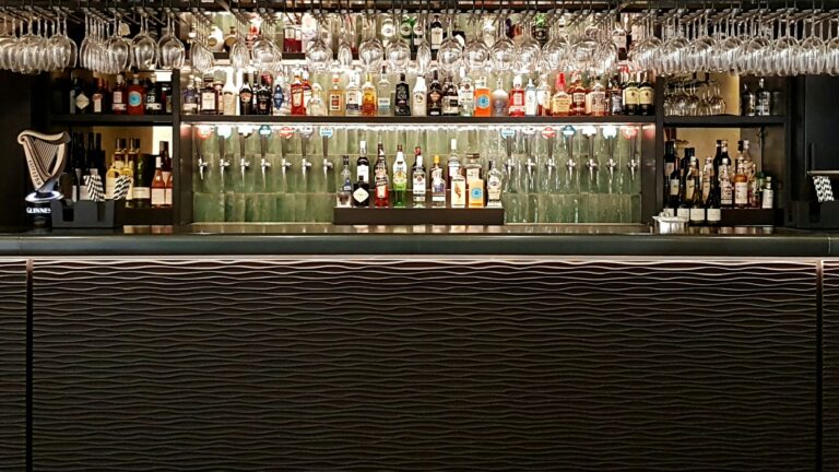 The back bar with glass racks and spirits shelving above a textured bar front, The Post Barn