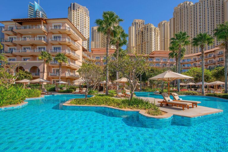 The resort gardens and lagoon pool beneath the low-rise hotel buildings, The Ritz-Carlton, Dubai