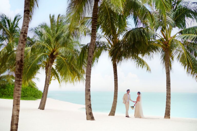 Couple on the beach among palm trees, The Ritz-Carlton Maldives, Fari Islands