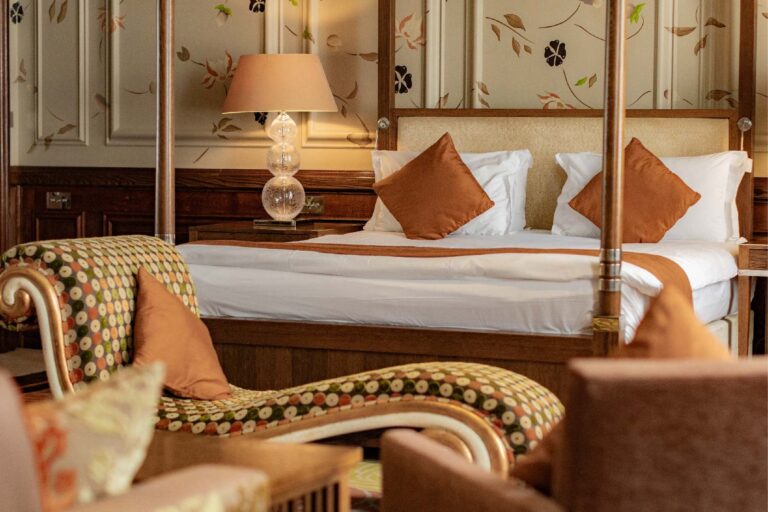 A four-poster suite in the Roseate building, with hand-painted panelling and a patterned chaise longue, The Roseate Reading