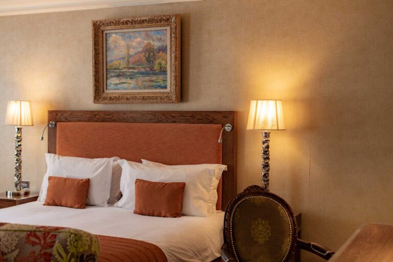 A traditional bedroom in the Roseate building, with an upholstered headboard and a landscape painting above the bed, The Roseate Reading