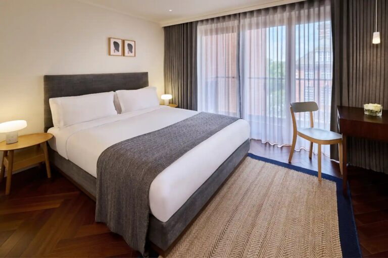 A bedroom in The House, the contemporary wing, with oak floors and a balcony window, The Roseate Reading