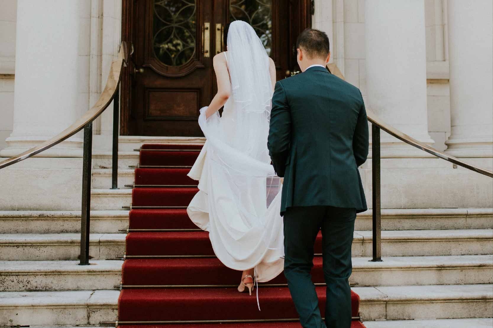 A couple walking up the red-carpeted entrance steps to the arched front door, The Roseate Reading