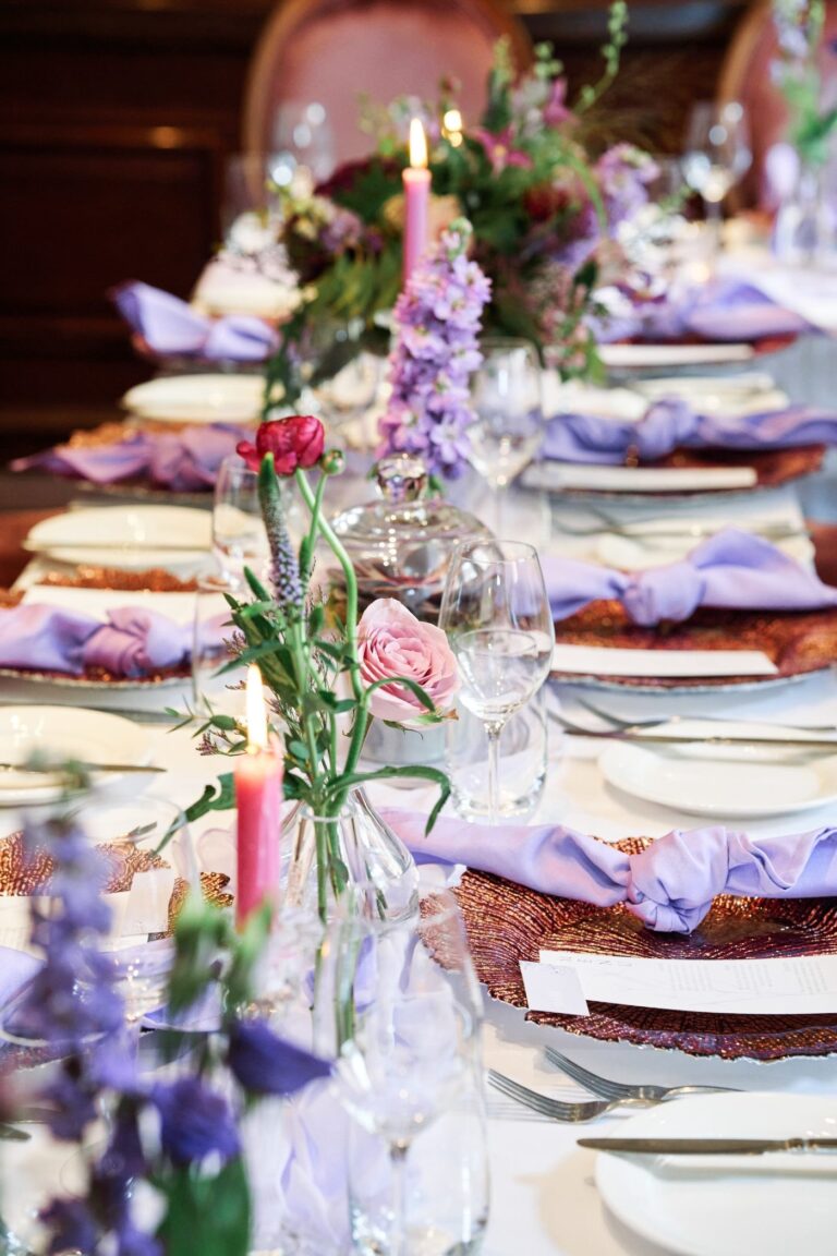 A wedding table dressed with lilac napkins, delphiniums and pink candles, The Roseate Reading