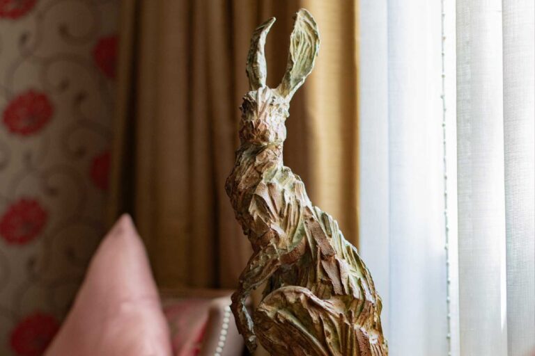 A bronze hare sculpture by a curtained window; the hotel says its art includes animal bronzes by Claire Norrington in every bedroom, The Roseate Reading