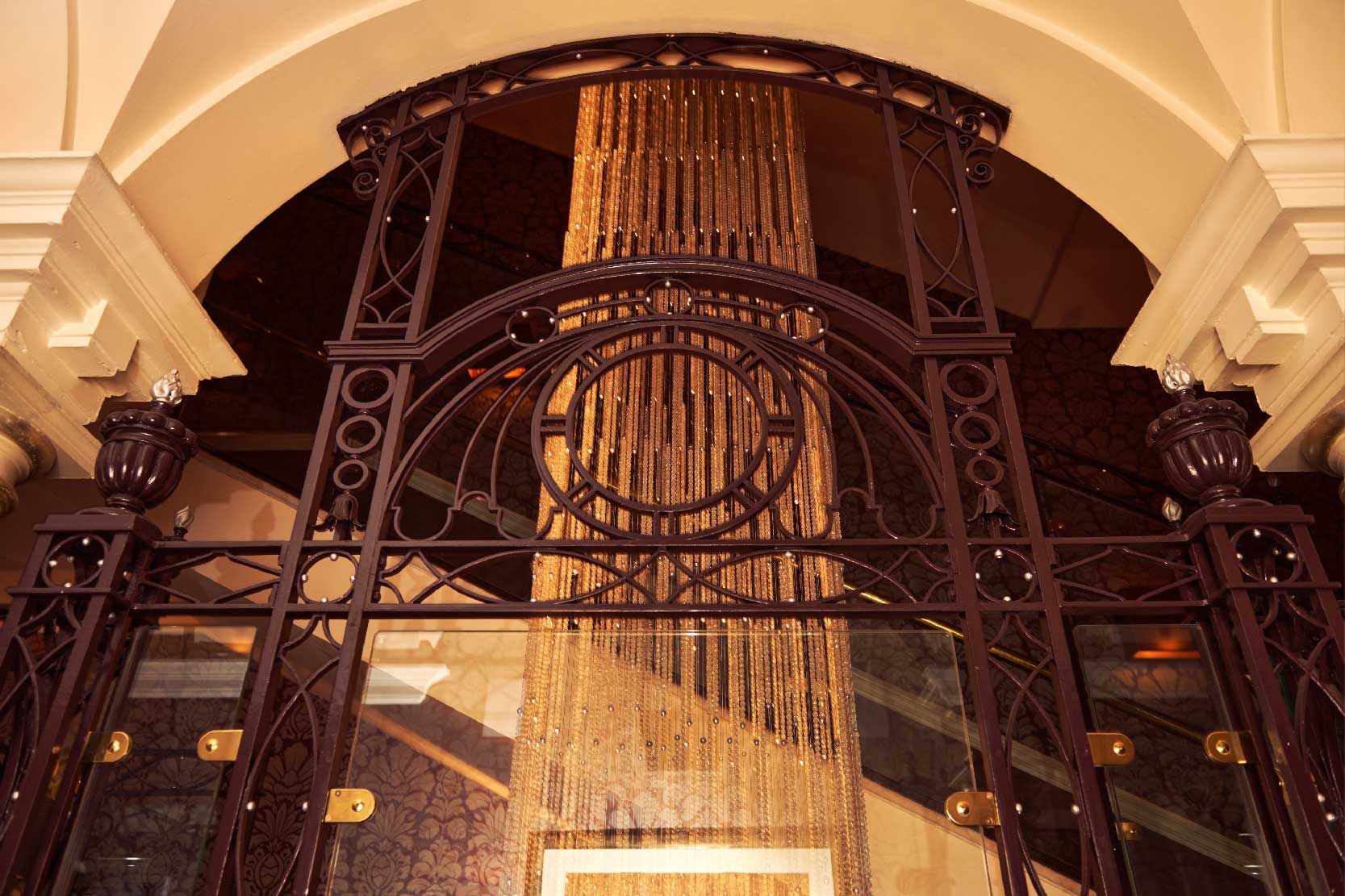 Looking up through the ironwork of the original lift shaft at the glass-bead chandelier that runs the height of the building, The Roseate Reading