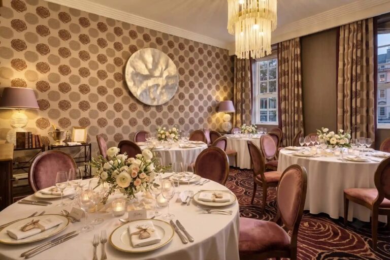 The Library laid with round tables and flowers under a crystal chandelier, The Roseate Reading