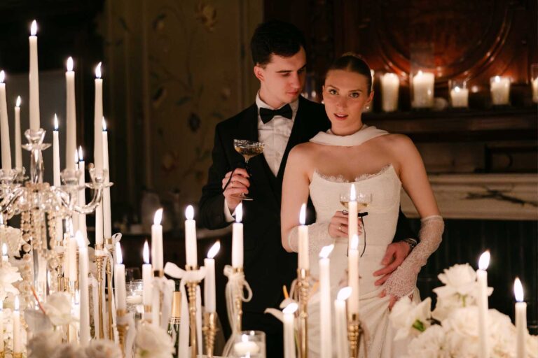 A couple with glasses raised behind a table of tall candles at an evening reception, The Roseate Reading