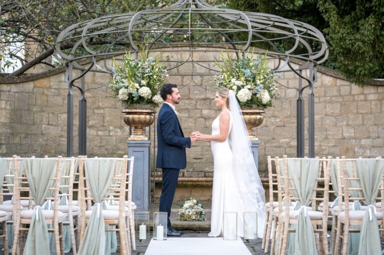 A couple exchanging vows beneath the pergola in the Wedding Garden, The Royal Crescent Hotel & Spa
