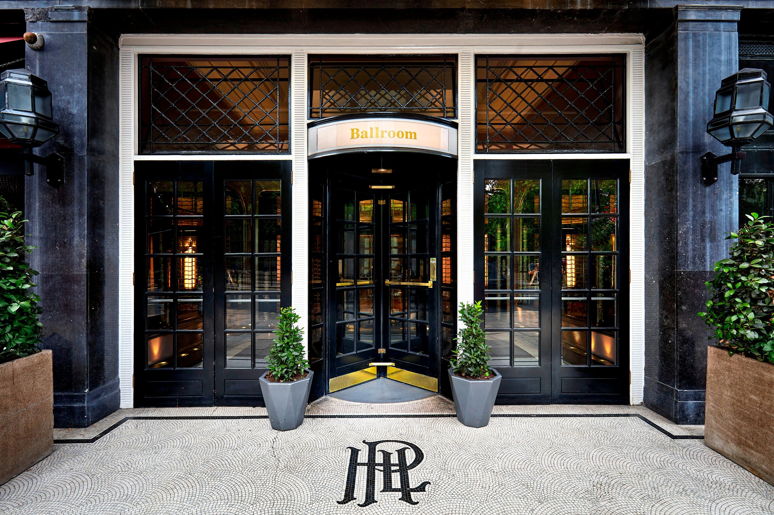 The separate street entrance to the Ballroom, with black lattice doors, a revolving door and topiary in planters, The Sheraton Park Lane Hotel
