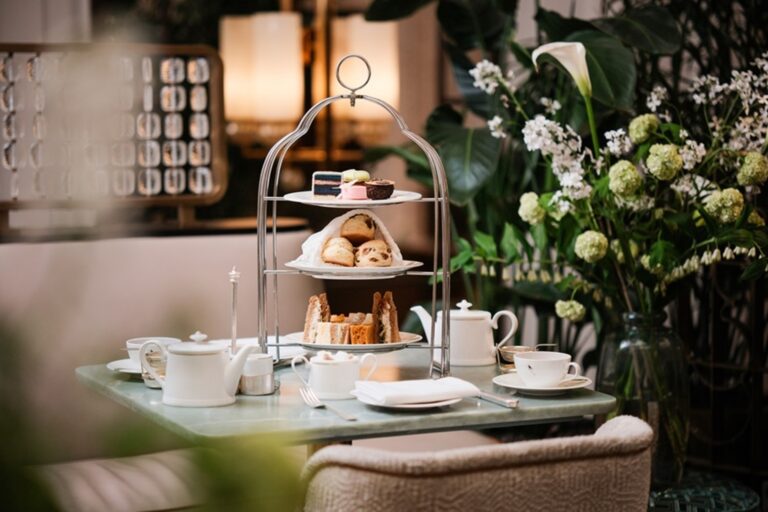 Afternoon tea in the Palm Court on a three-tier birdcage stand, with white flowers on the table, The Sheraton Park Lane Hotel