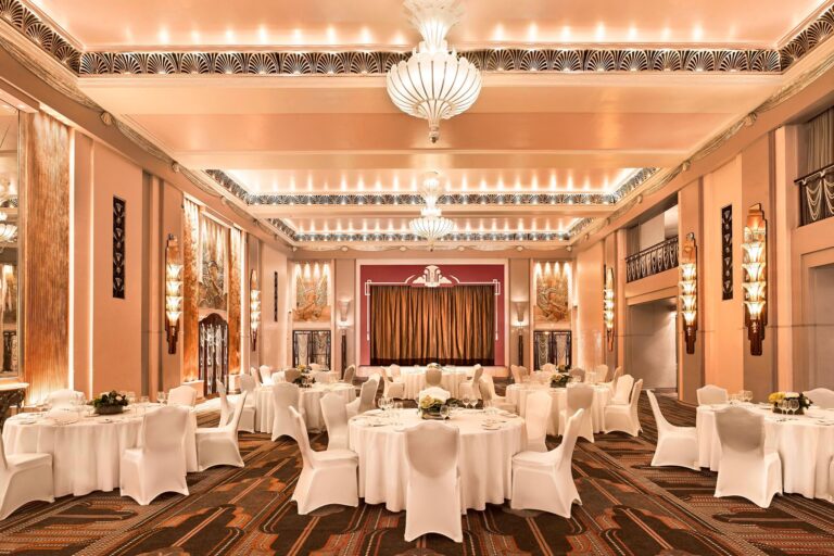 The Ballroom laid for a banquet beneath its chandeliers, with the stage curtain at the far end and the balcony along the side, The Sheraton Park Lane Hotel