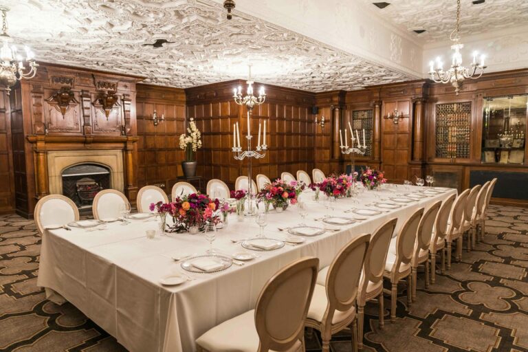 The oak-panelled Oak Room with a carved plaster ceiling, set with one long table, candelabra and pink flowers, The Sheraton Park Lane Hotel