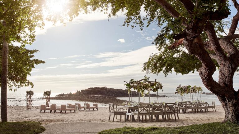 Tables set on the beach beneath a large tree, The St. Regis Punta Mita Resort