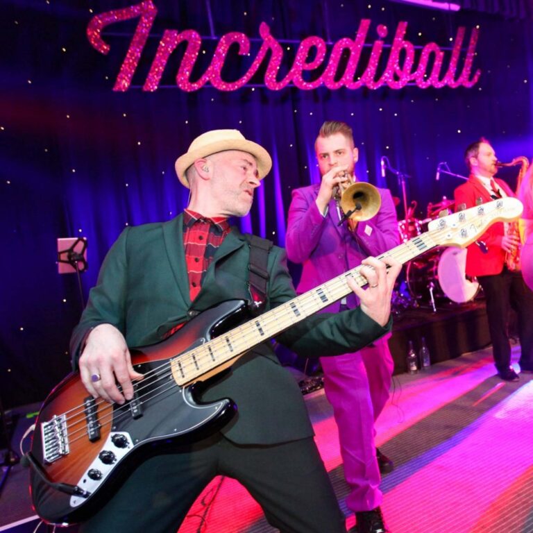 Bass guitar and trumpet on stage in front of an Incrediball sign, The Sway Allstars