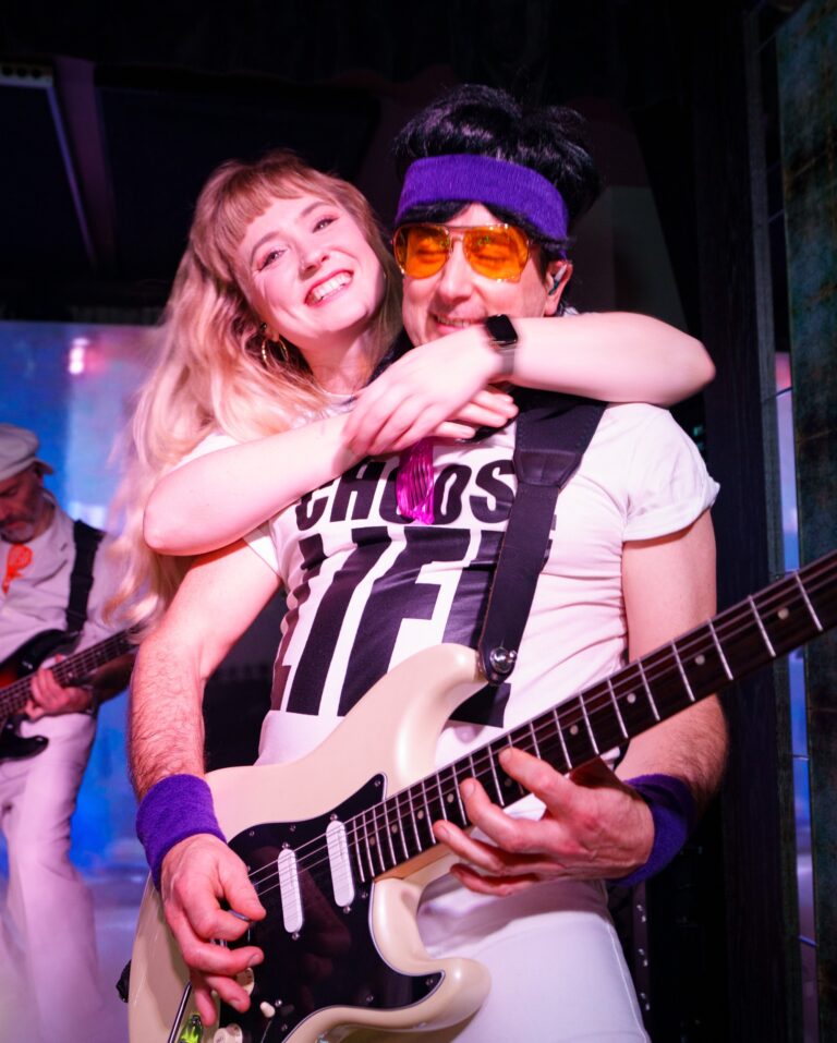 A guitarist and singer in 80s costume during a set, The Sway Allstars