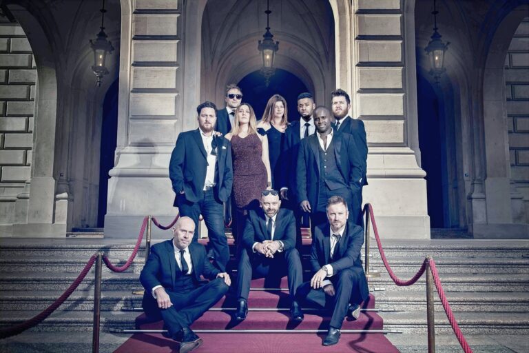 The band in black tie on red carpeted steps outside a stone building, The Sway Allstars