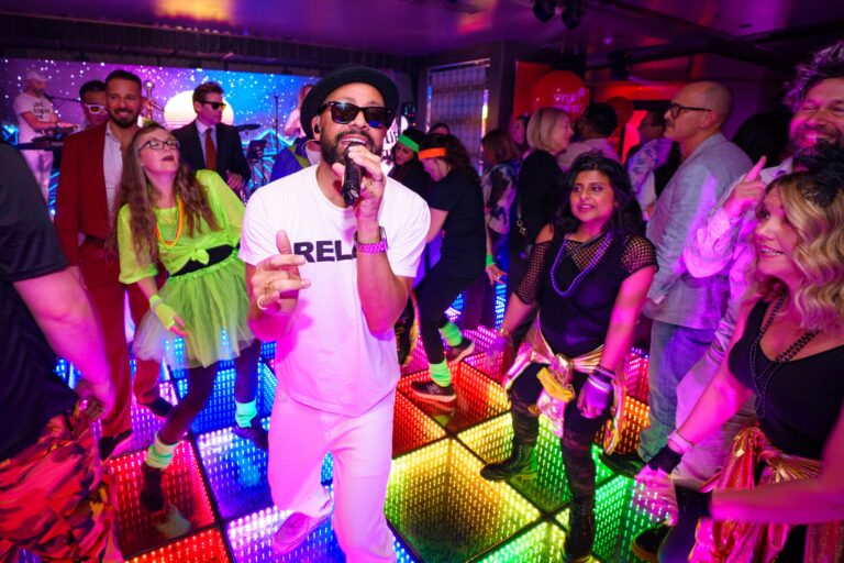 A singer working the crowd at a party on an illuminated dance floor, The Sway Allstars