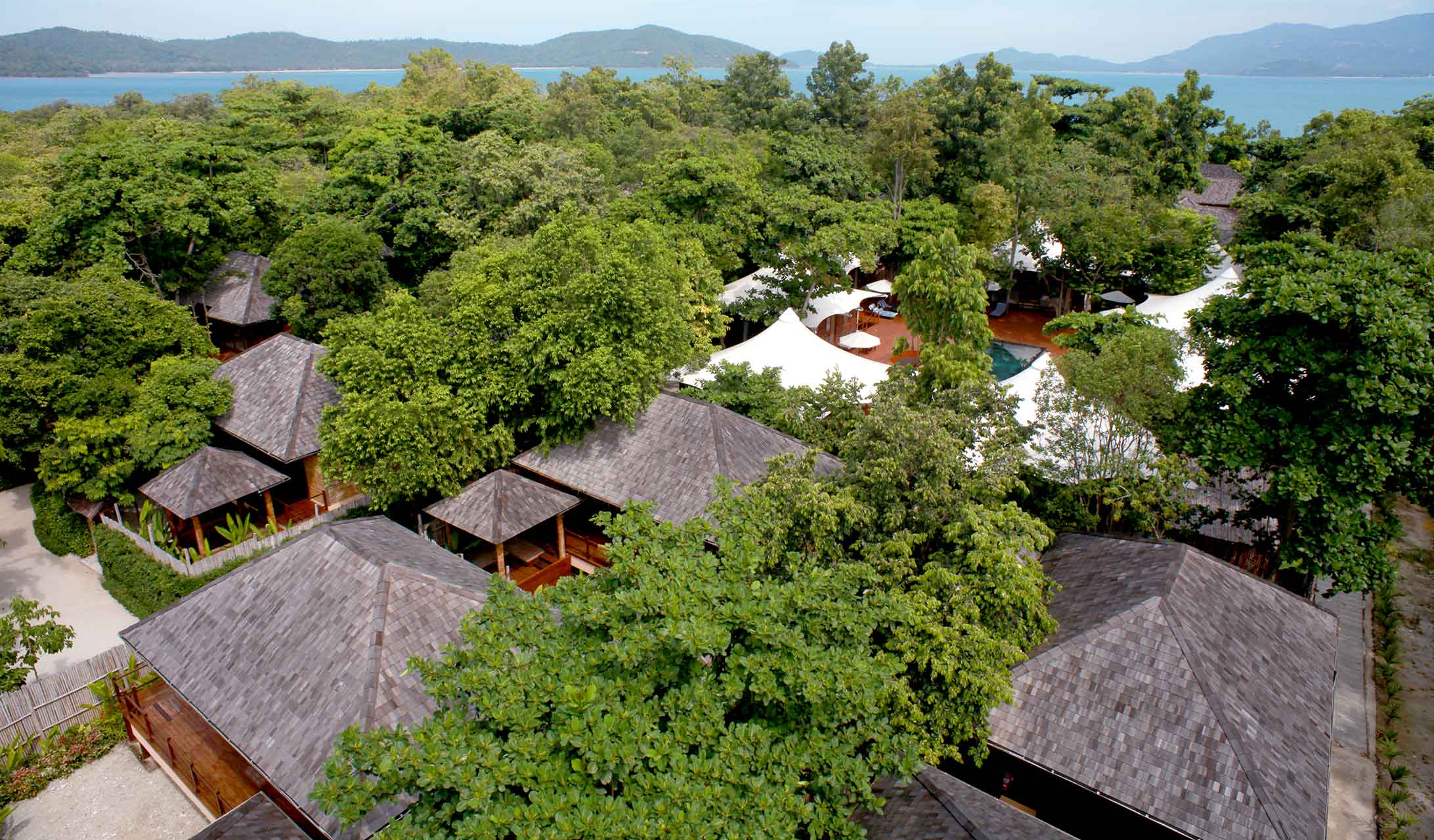 Aerial view of the villa roofs among the trees on Koh Madsum, with the Gulf of Thailand beyond, The Treasure Resort Koh Madsum - Samui