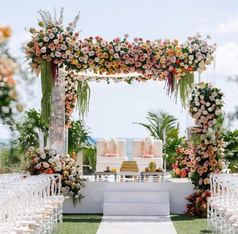 A ceremony arch of flowers set by the water, The Wedding Atelier