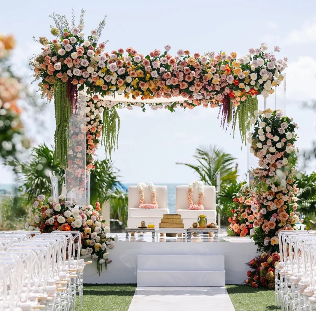 A ceremony arch of flowers set by the water, The Wedding Atelier
