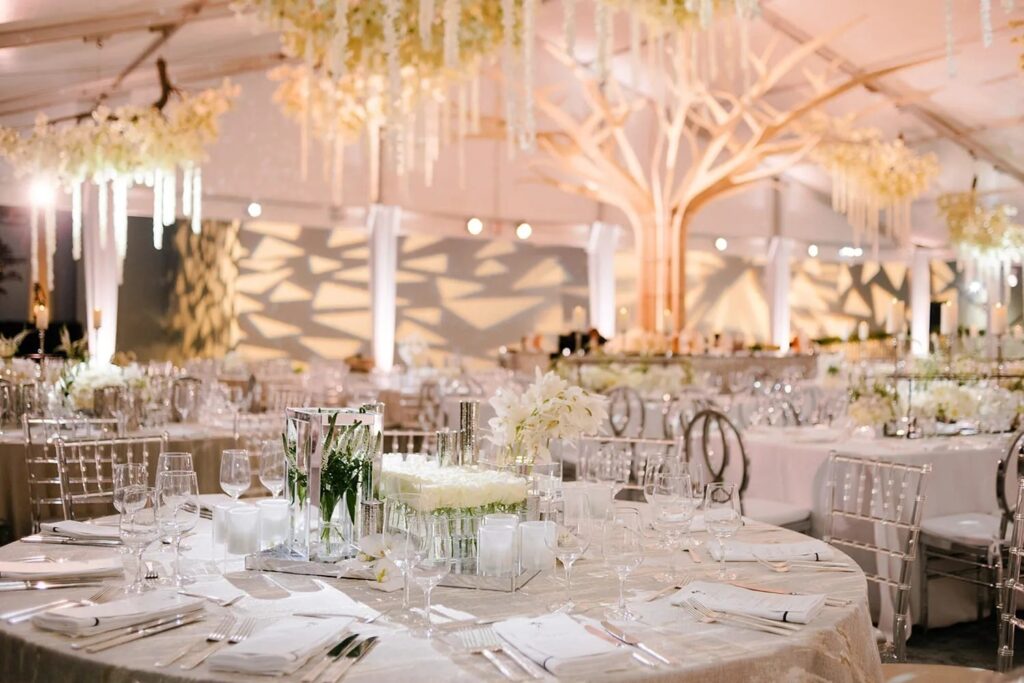 A pale reception hall with chandeliers and round tables, The Wedding Atelier