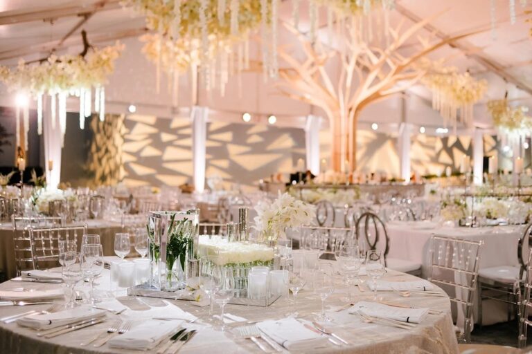 A pale reception hall with chandeliers and round tables, The Wedding Atelier