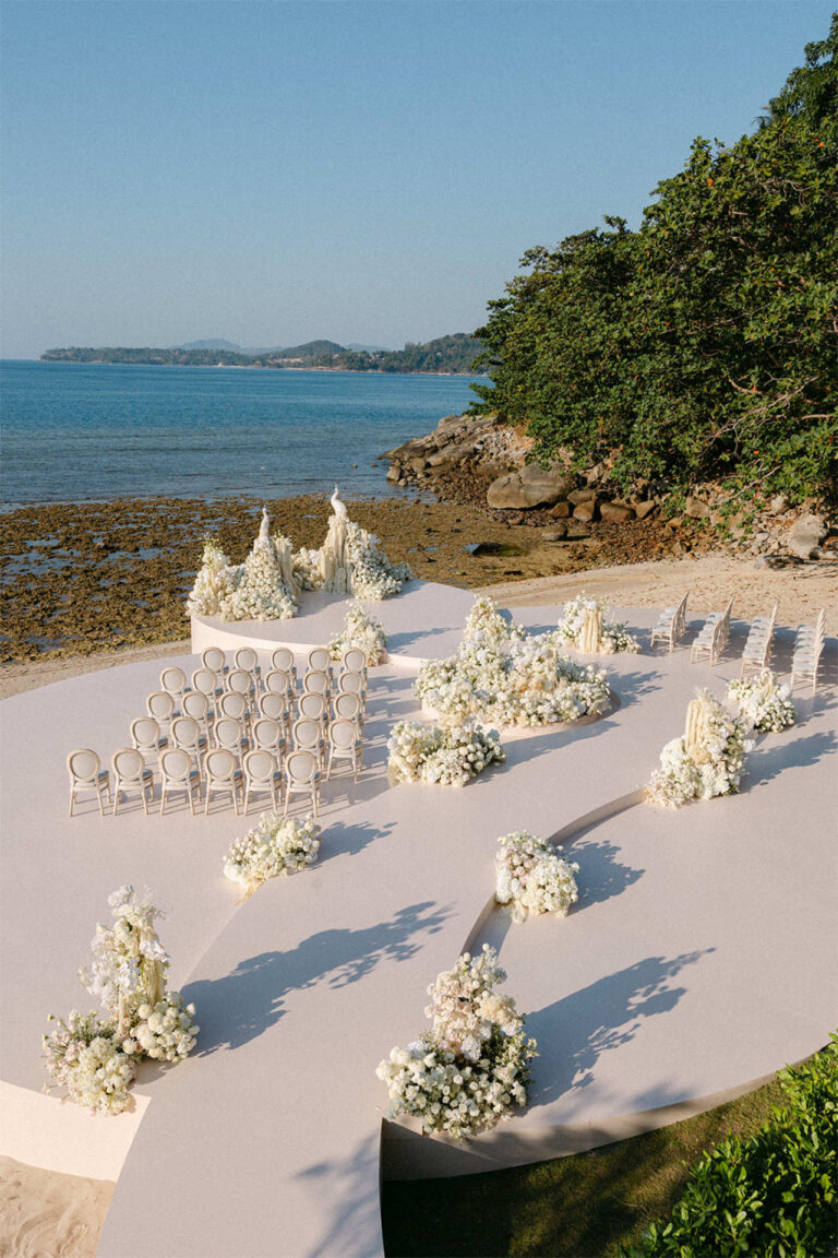 Ceremony chairs between low clusters of white flowers above the sea, The Wedding Bliss - Thailand