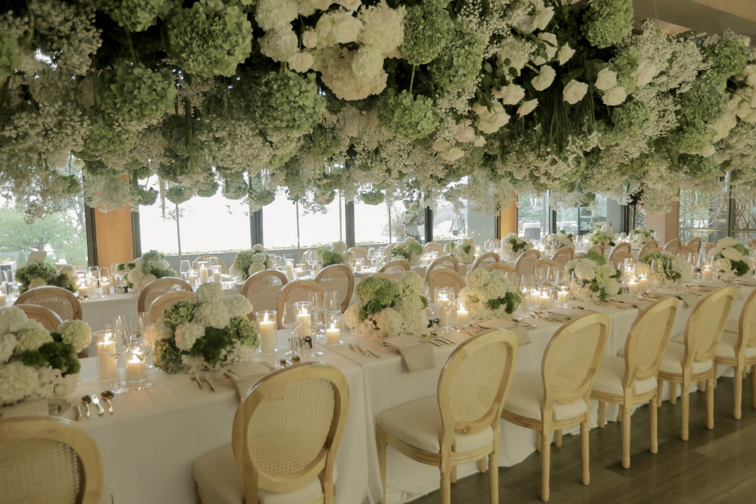 Long candlelit tables beneath a ceiling of white hydrangeas and hanging blooms, The Wedding Bliss - Thailand