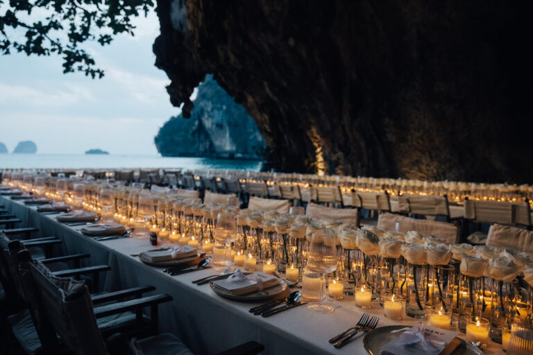 A very long table of candles on the beach under a limestone cliff at dusk, The Wedding Bliss - Thailand