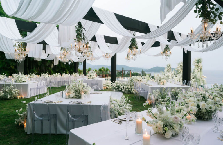 White drapes and chandeliers over garden tables dressed in white flowers, The Wedding Bliss - Thailand