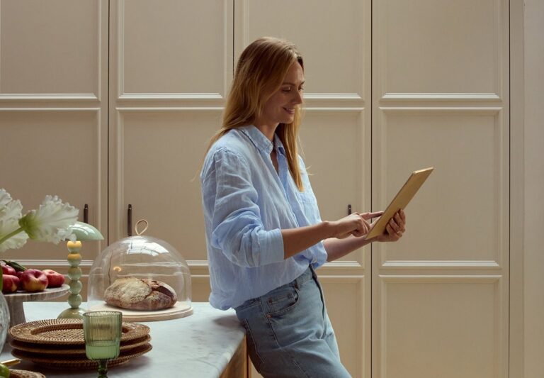 A woman using a tablet in the kitchen to plan a gift list, The Wedding Shop