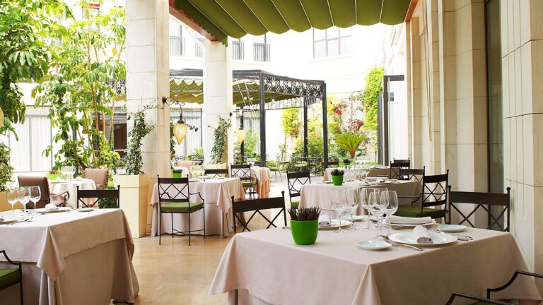 The restaurant terrace opening onto the garden beneath a green awning, greenery all around, The Westin Valencia