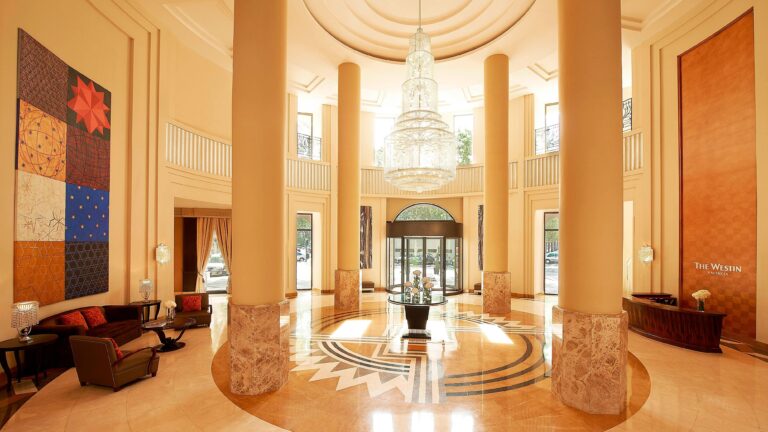 The grand lobby, marble columns rising to a crystal chandelier over a patterned stone floor, The Westin Valencia