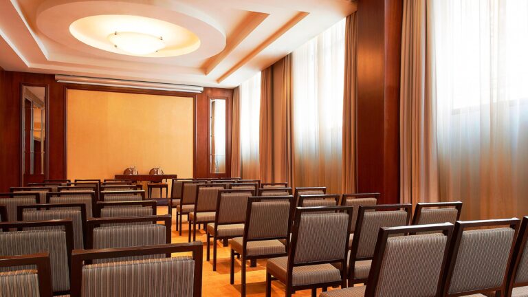 A daylit salon set theatre-style for a gathering beneath crystal chandeliers, The Westin Valencia
