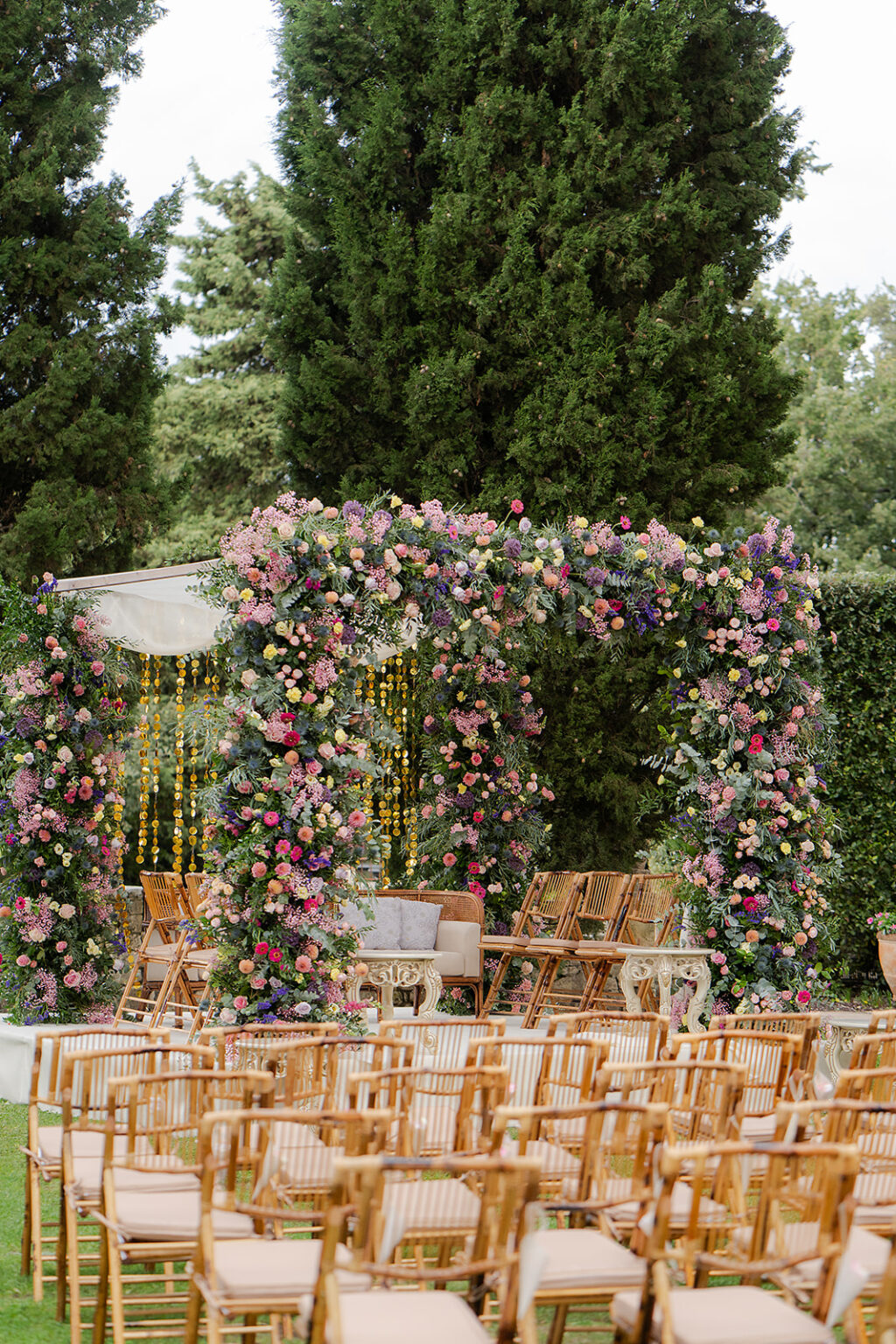 Flower-covered mandap and seating for the Indian ceremony in the garden at Borgo Pignano, Tuscany, TheKnotInItaly