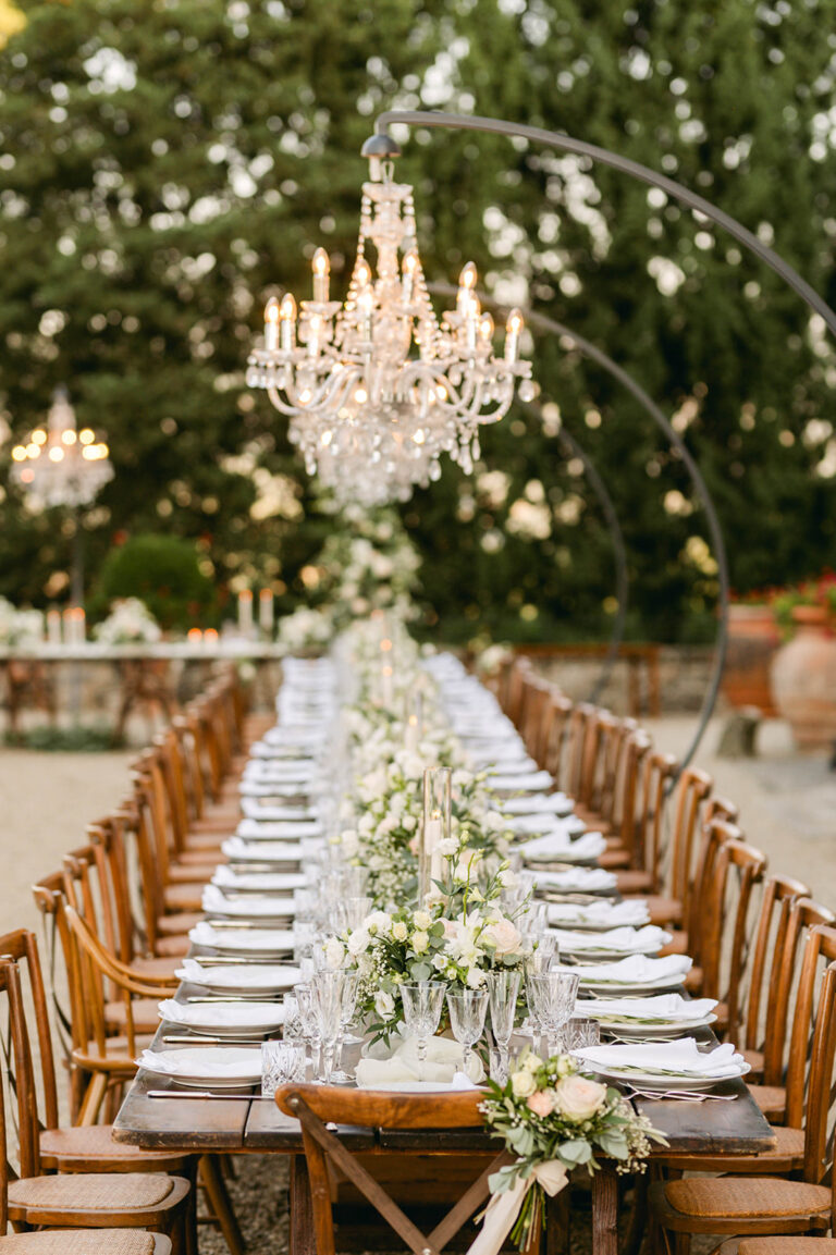Long dinner table under a hanging chandelier on the castle terrace, Castello di Vicchiomaggio, Chianti, TheKnotInItaly