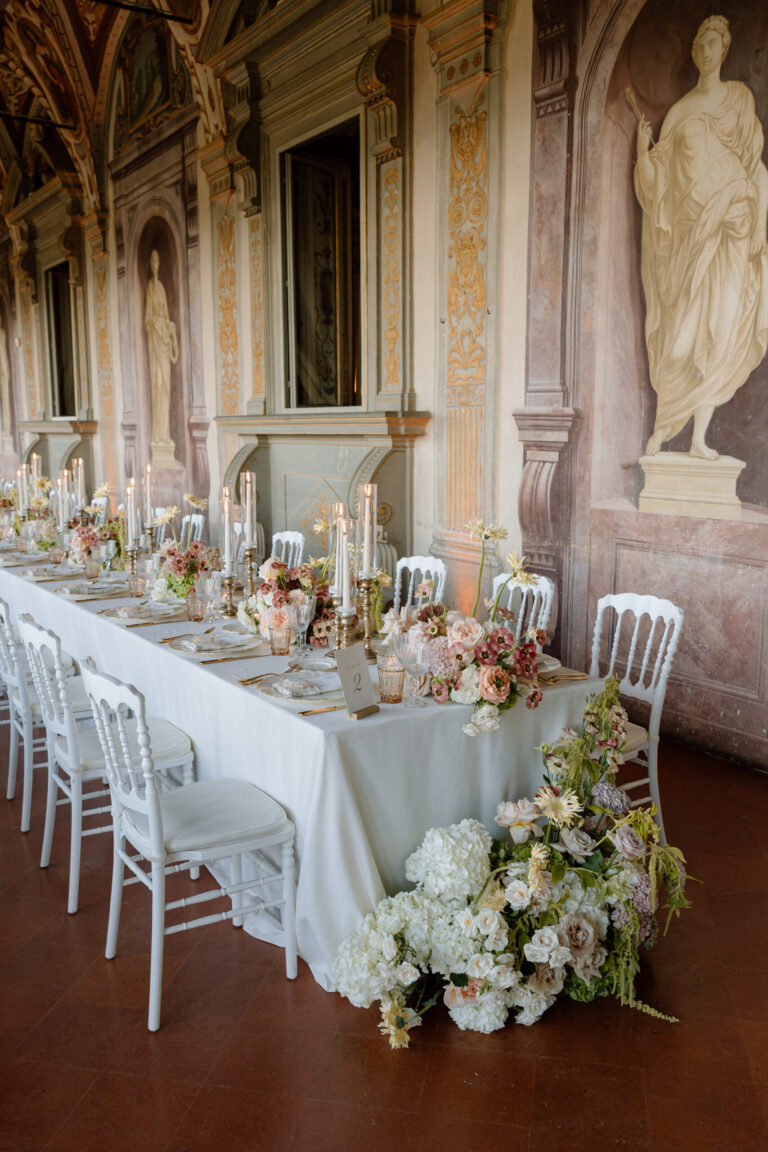 Pastel flowers, candlesticks and white chairs along the gallery table at Villa Corsini a Mezzomonte, TheKnotInItaly