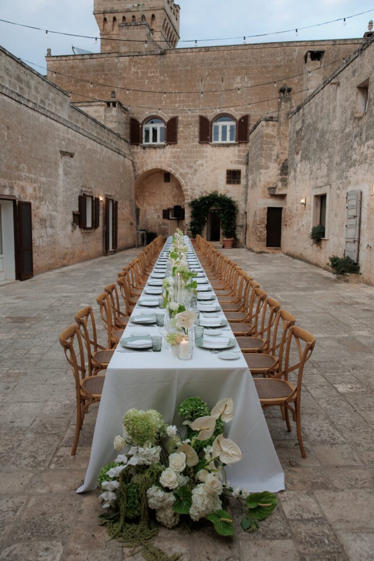 A single long table with white flowers in the courtyard of Masseria Salamina, Puglia, TheKnotInItaly