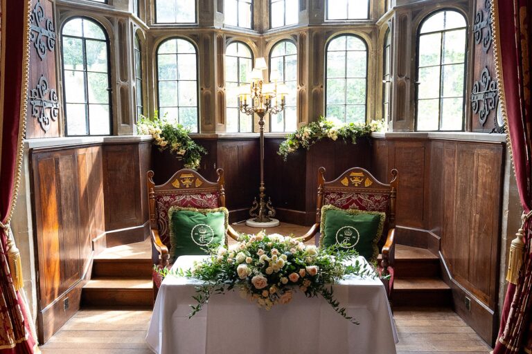 A ceremony table with two carved chairs in a panelled oriel window bay, Thornbury Castle