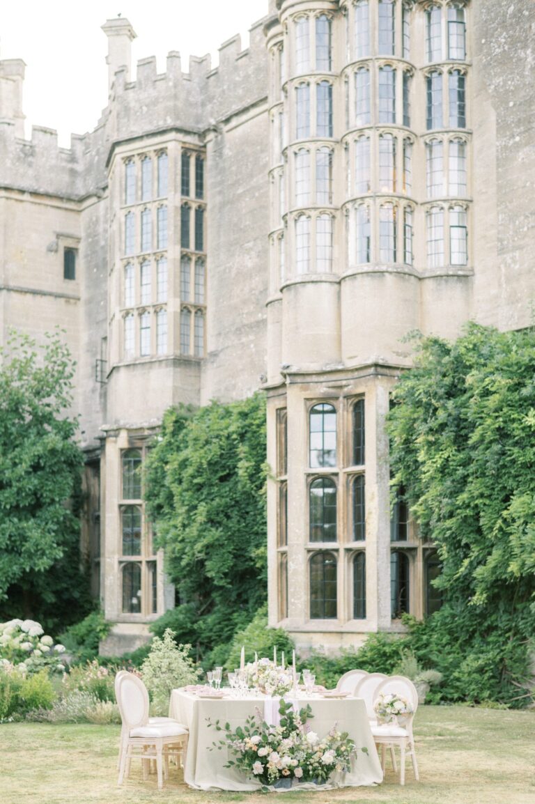 A small dinner table laid on the lawn beneath the castle's oriel windows, Thornbury Castle
