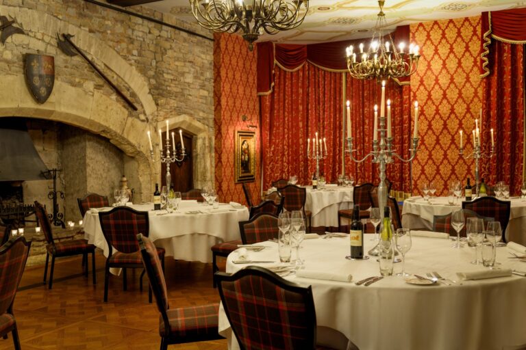 The Tudor Hall set with round tables, candelabra and a stone fireplace, Thornbury Castle