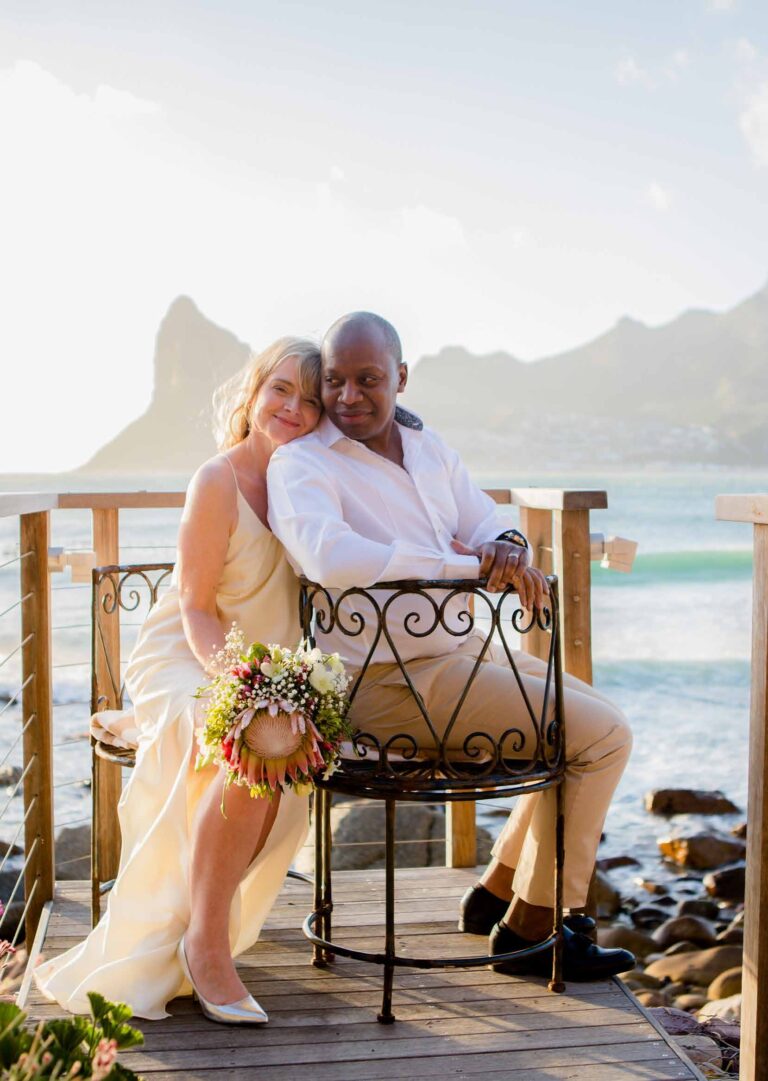 The couple on a wrought-iron bench on the deck, Hout Bay and the Sentinel behind, Tintswalo Atlantic