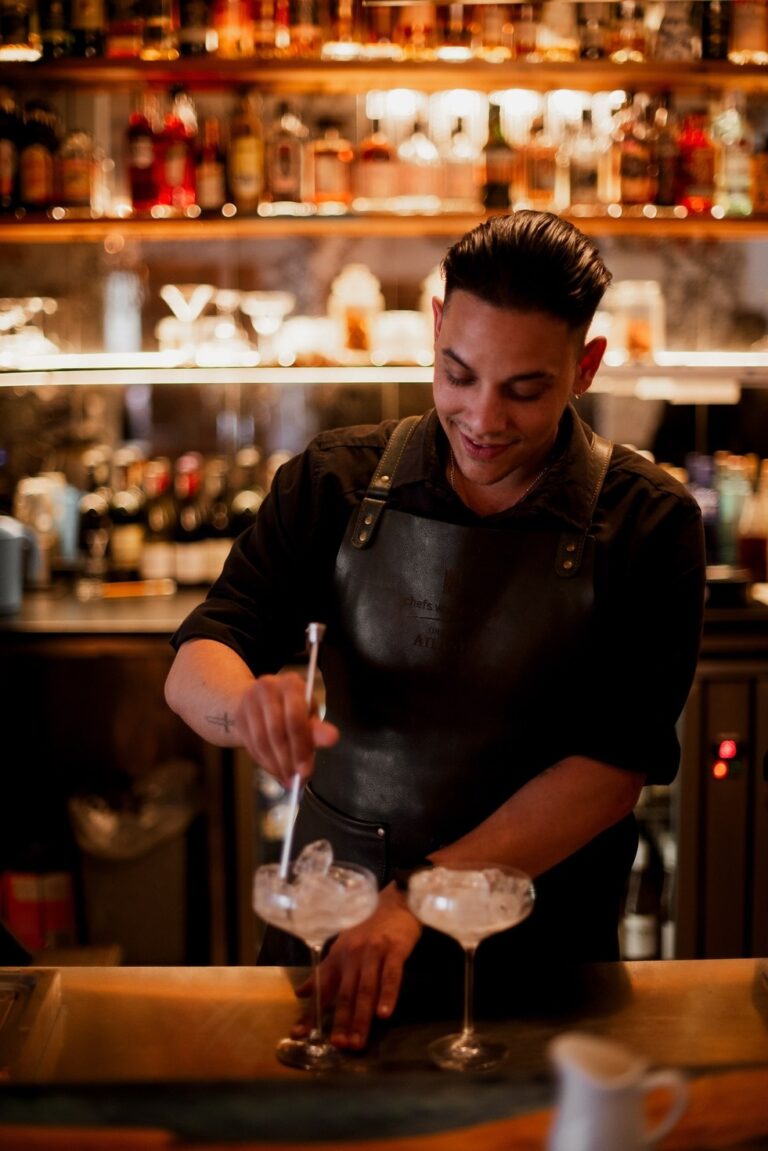 The bartender mixing cocktails at the lit back bar, Tintswalo Atlantic